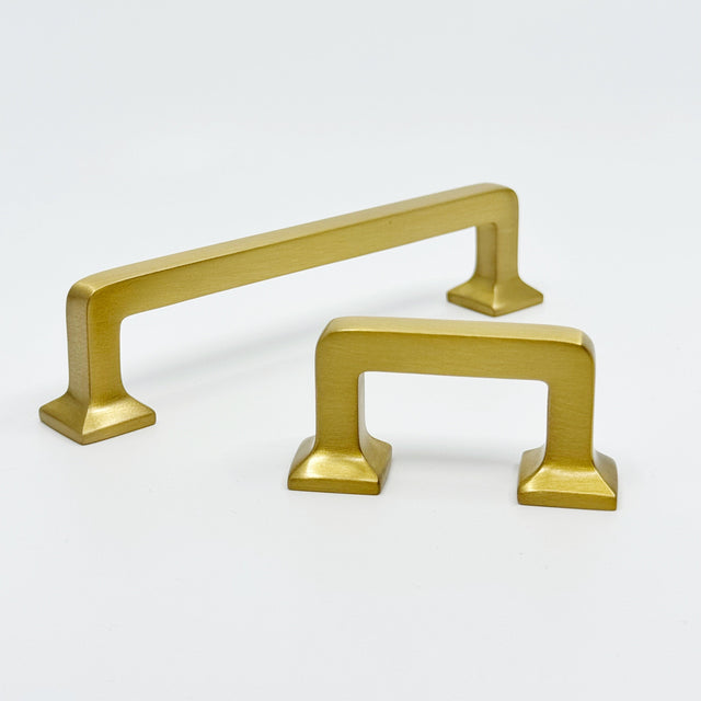Two gold cabinet handles on a white background
